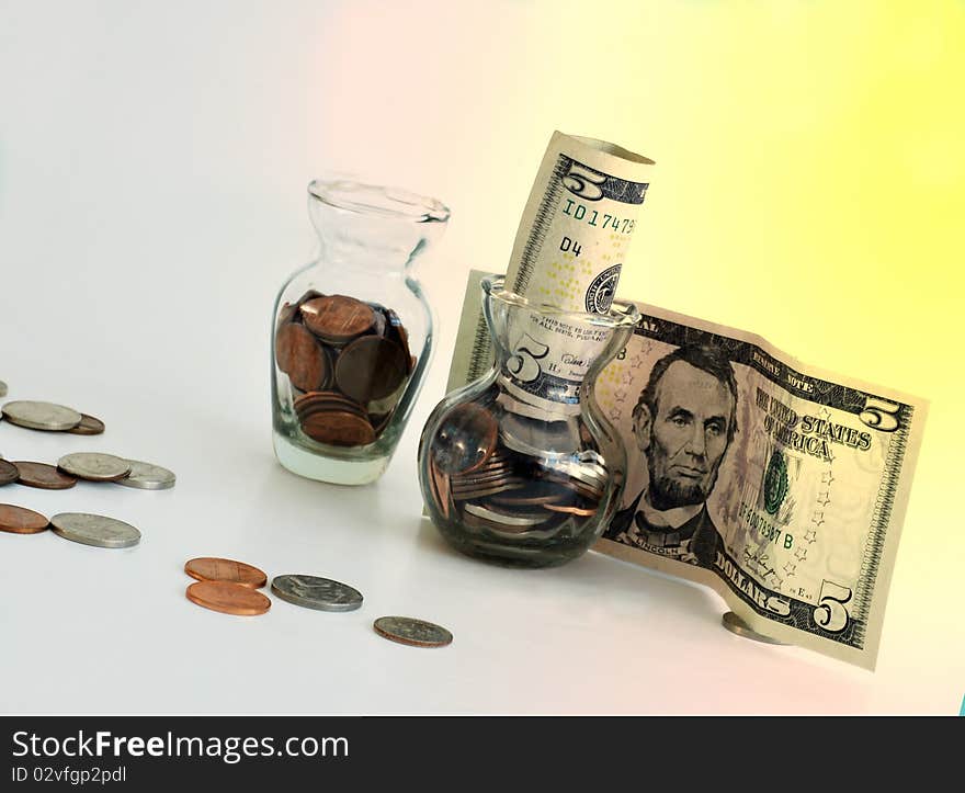 Coins in class jars and $5 bills with colorful background. Coins in class jars and $5 bills with colorful background