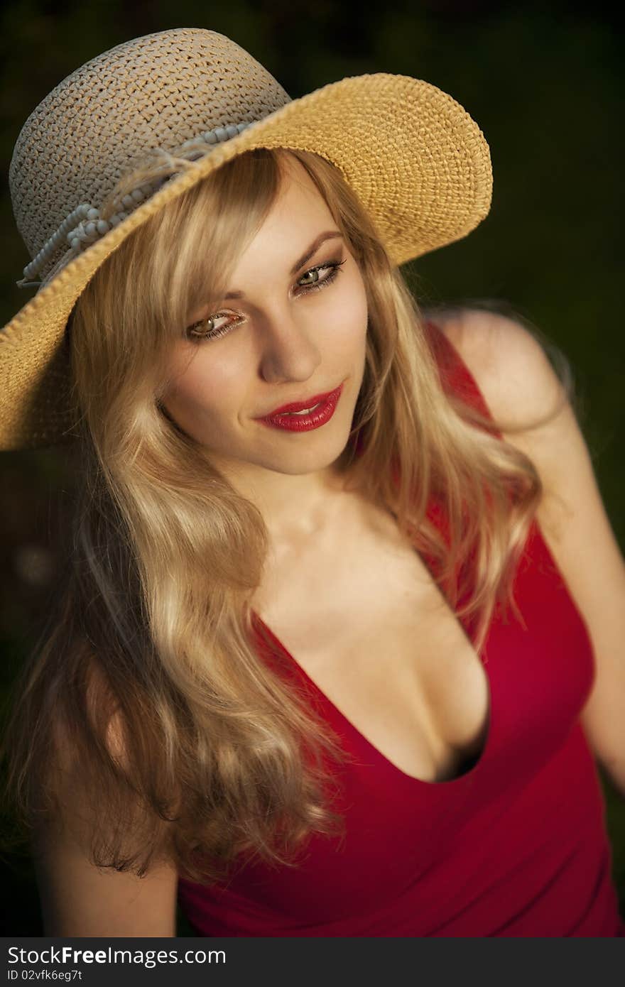 High angle view of fashionable young blond woman with straw hat, black background.