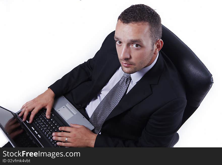 Successful businessman in his chair, with laptop, working and looking at camera, isolated on white. Successful businessman in his chair, with laptop, working and looking at camera, isolated on white