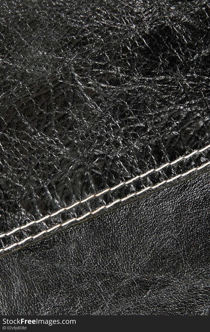 Stitch on shiny black leather with detailed texture.