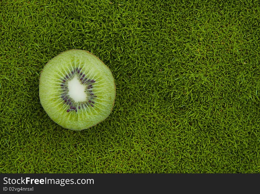 A kiwifruit on green grass background. A kiwifruit on green grass background