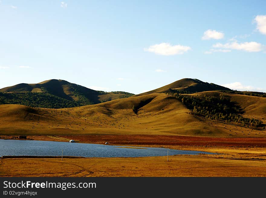 Grasslands; lakes and hills in the background blue sky. Grasslands; lakes and hills in the background blue sky