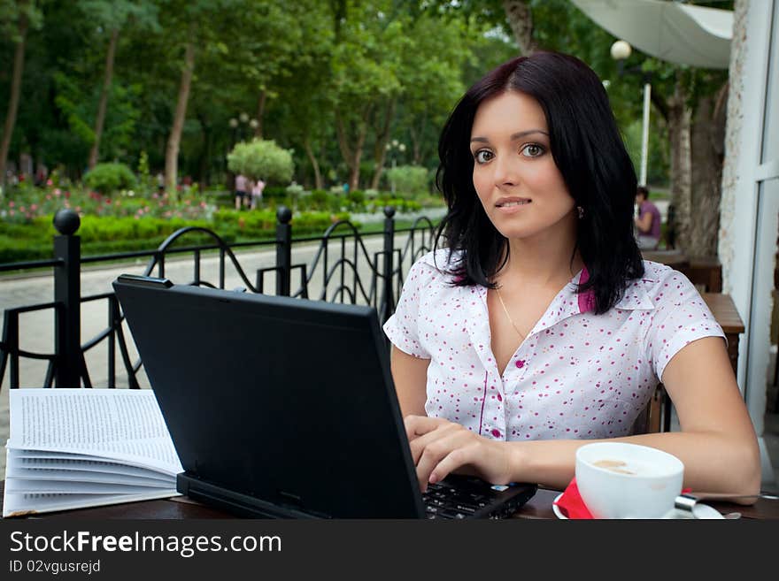 Young beautiful student girl with laptop and cup of coffee in cafe. Young beautiful student girl with laptop and cup of coffee in cafe