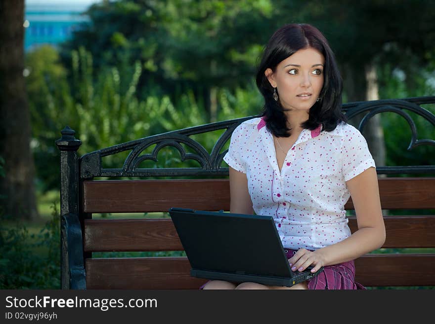 Young beautiful student girl with laptop in the park. Young beautiful student girl with laptop in the park