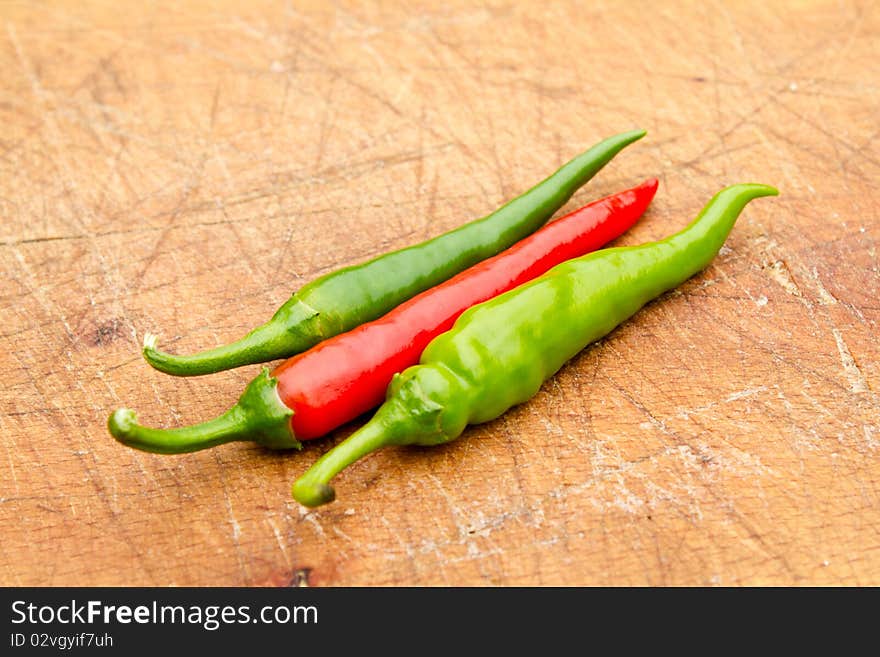 Three chilli peppers on a cutting board (shallow DOF). Three chilli peppers on a cutting board (shallow DOF)