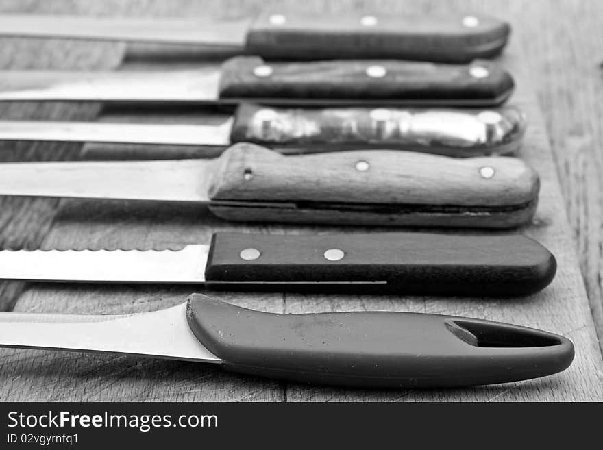 Several old, used knives on a cutting board. Several old, used knives on a cutting board