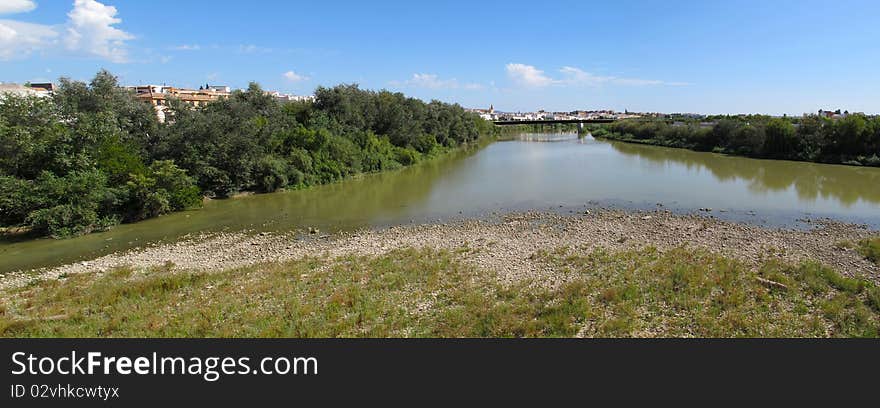 The Guadalquivir River filters through banks, trees and and the Puente Romano Bridge along the banks of Cordoba where one block away is the Cordoba Cathedral formerly known as the Mezquite The Great Mosque. The Guadalquivir River filters through banks, trees and and the Puente Romano Bridge along the banks of Cordoba where one block away is the Cordoba Cathedral formerly known as the Mezquite The Great Mosque.