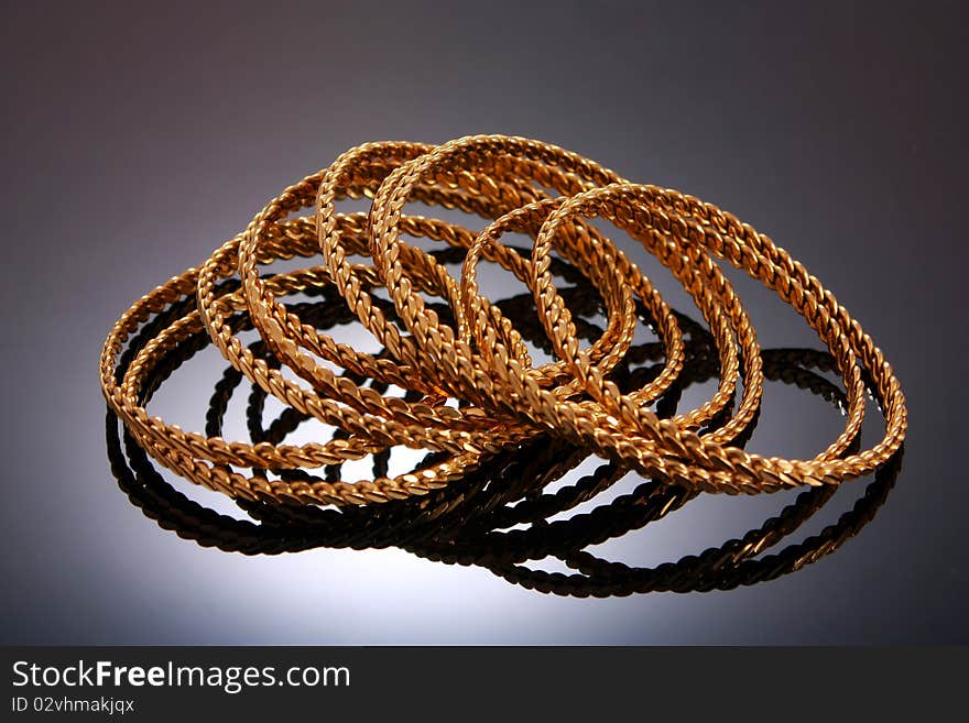 Gold bracelets isolated on black background with reflection