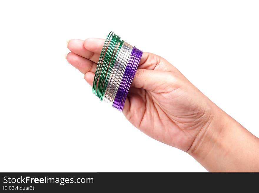 Female hand holding metal bangles on white background.