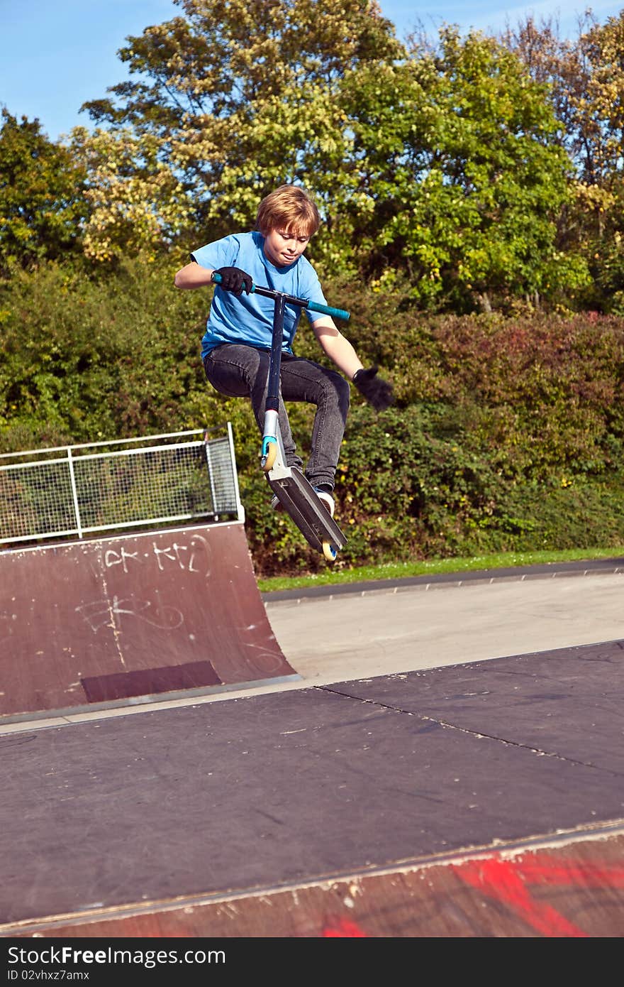 Young boy going airborne with his scooter at the skate park