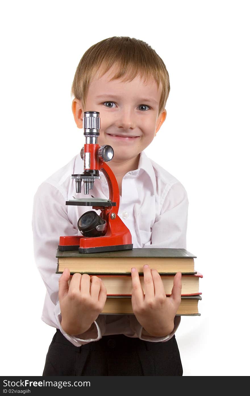 Happy boy with a stack of books and microscope on a white background