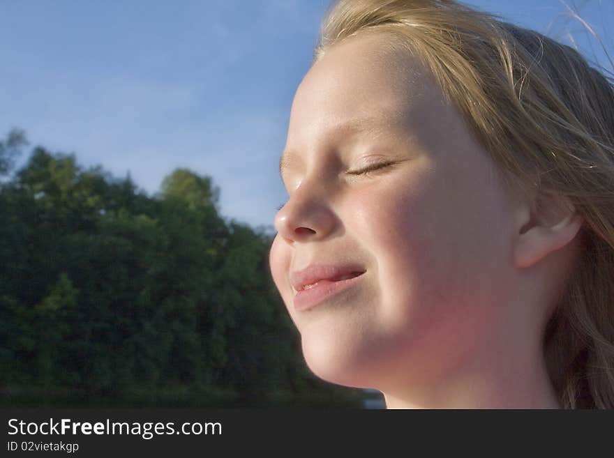 Happy little girl smiling in the sunshine and blowing summer wind. Happy little girl smiling in the sunshine and blowing summer wind.