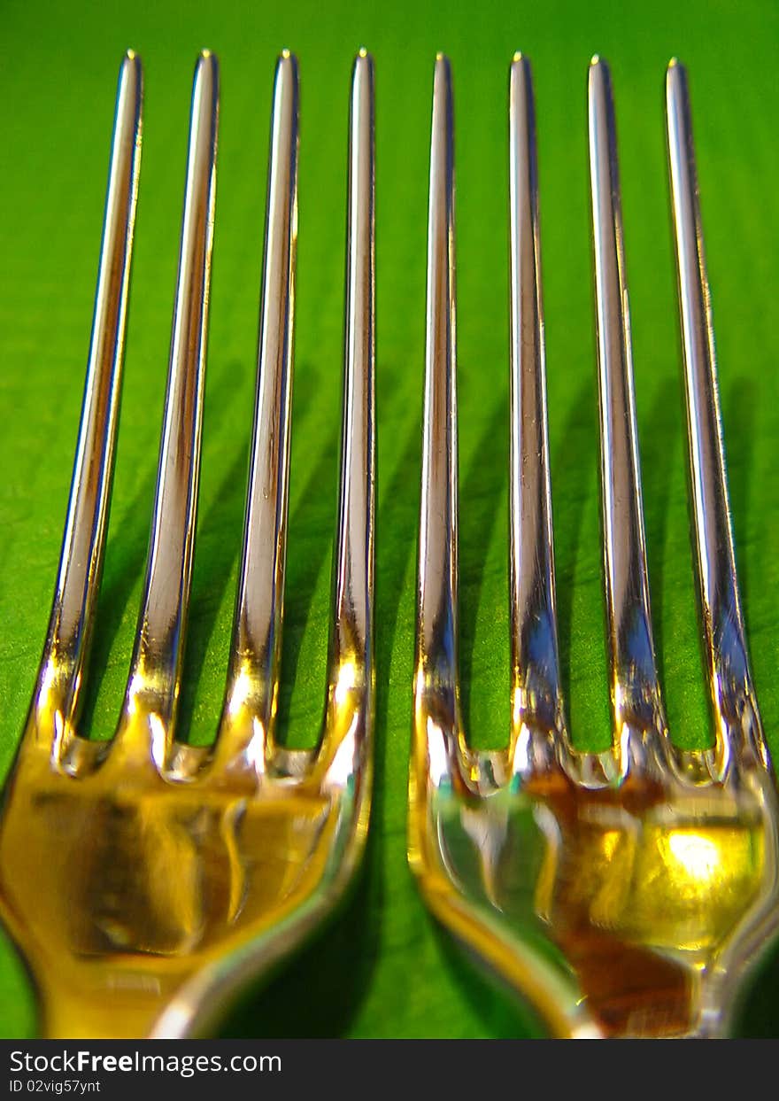 Long shiny forks on green table cloth