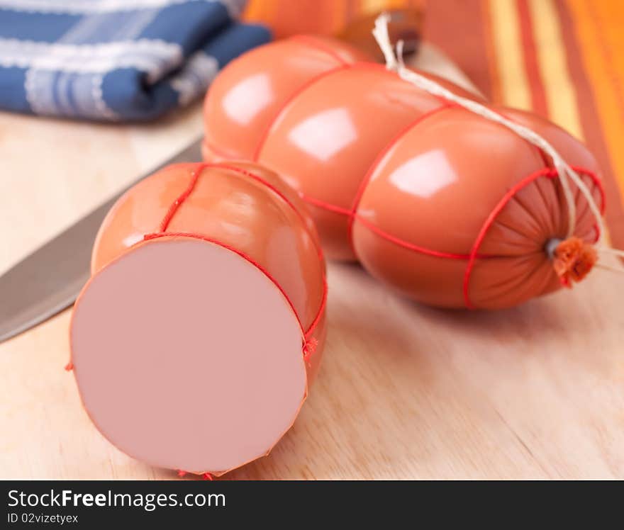 Boiled sausage, on a wooden cutting board.