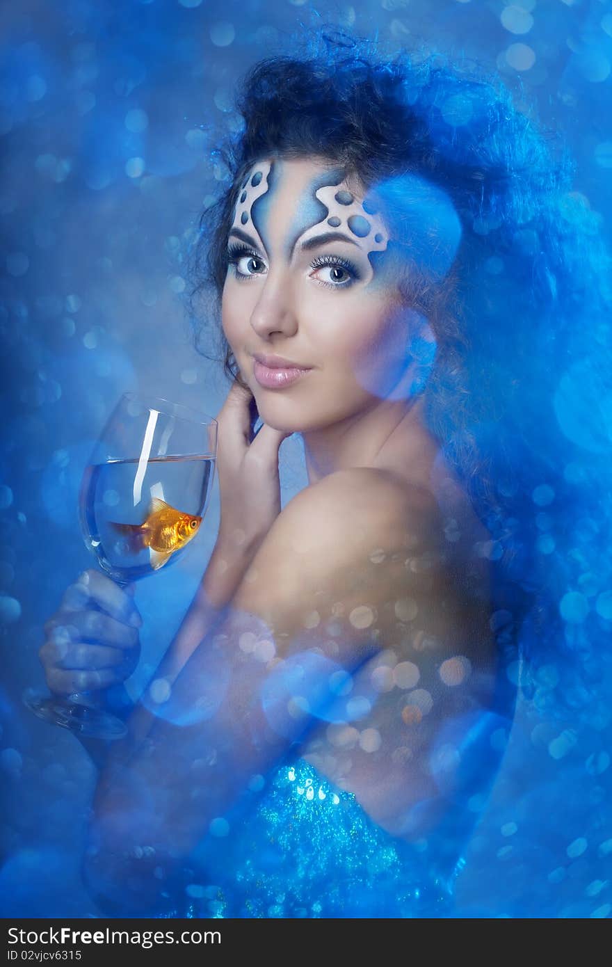 Girl with makeup, with a fish in a glass