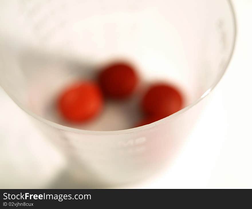 Close up shot of medicine cup with blurred red tablets