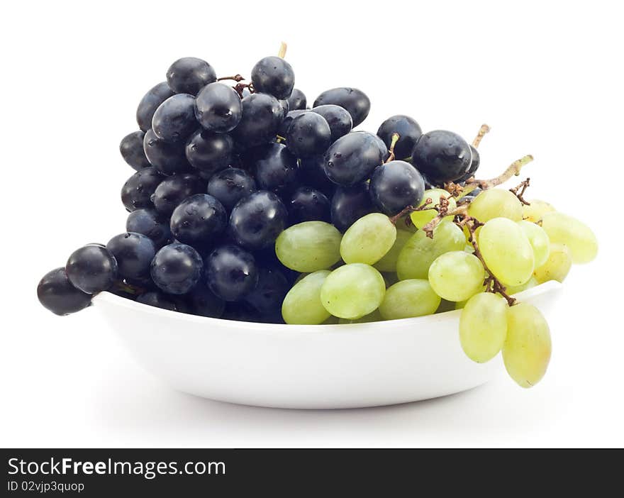 Branch of green and black grapes on a plate, white background