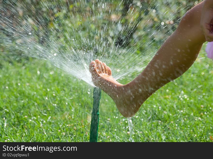 Female leg with the sprinkler on the green lawn. Female leg with the sprinkler on the green lawn