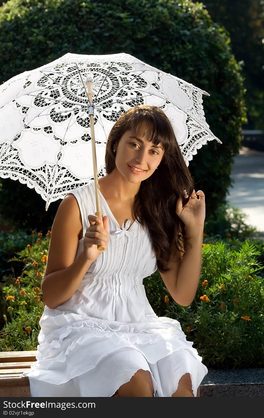 Smiling young attractive girl with sun umbrella sitting on the bench in the park. Smiling young attractive girl with sun umbrella sitting on the bench in the park