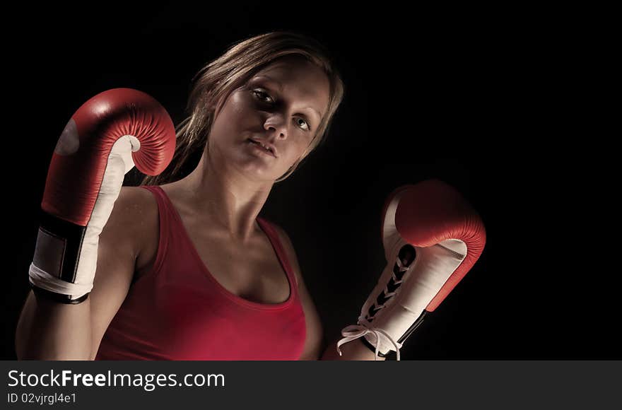 Young beautiful boxer girl over black background