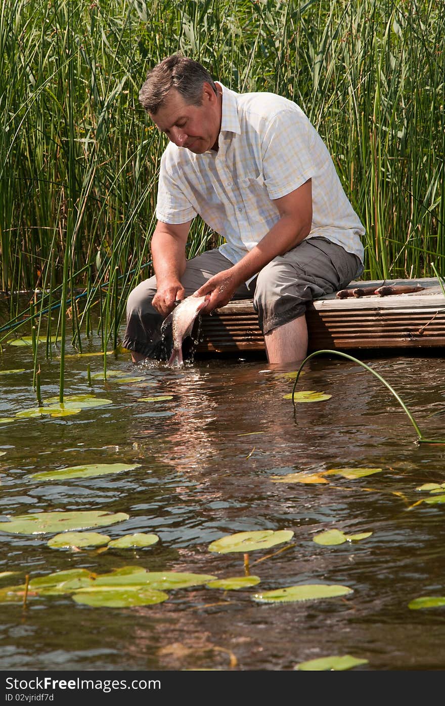 Happy senior man scaling fish