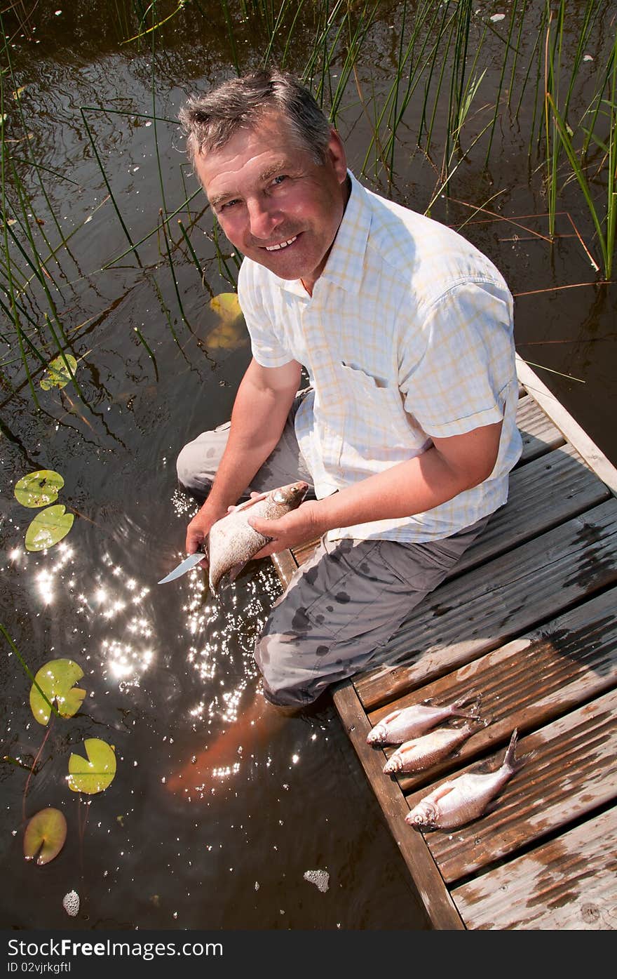 Happy senior man scaling fish