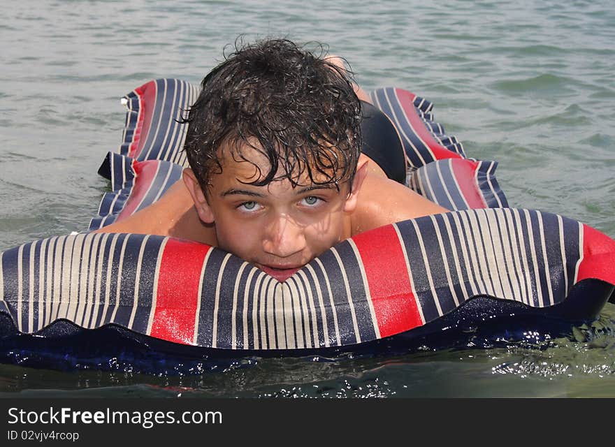 A young man enjoying the warm sun, floating on sea water. A young man enjoying the warm sun, floating on sea water