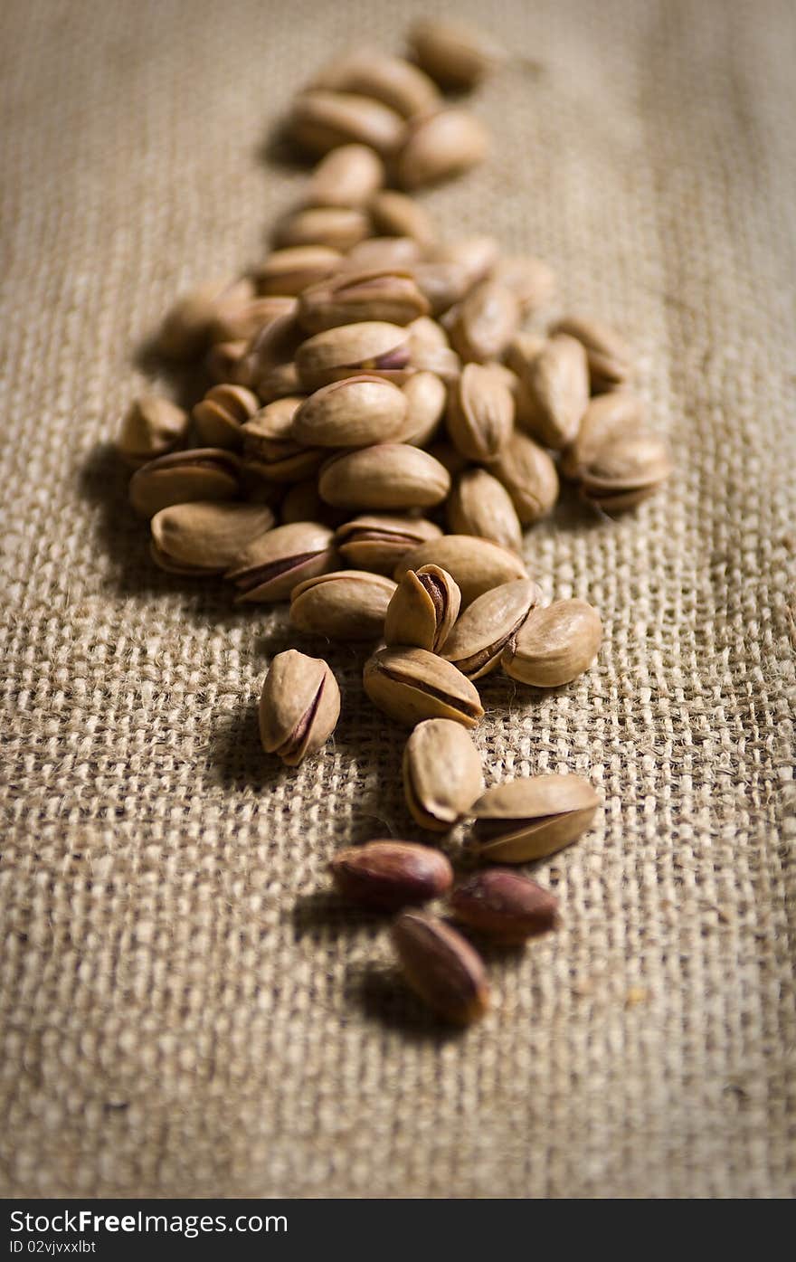 Burlap sack with pistachios salt spilling out over a white background. Burlap sack with pistachios salt spilling out over a white background