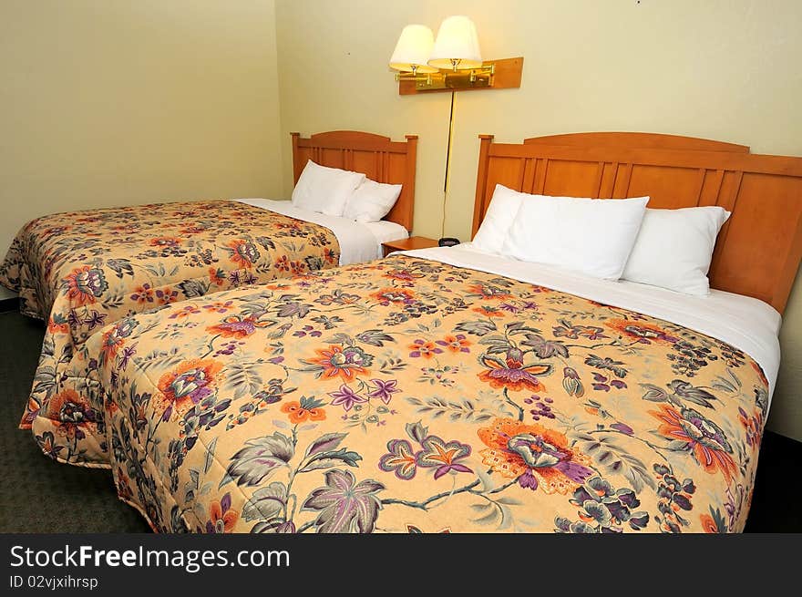 Double queen sized beds in generic hotel room. Suitable for concepts such as luxury, travel, tourism, vacation and holiday, and relaxation.