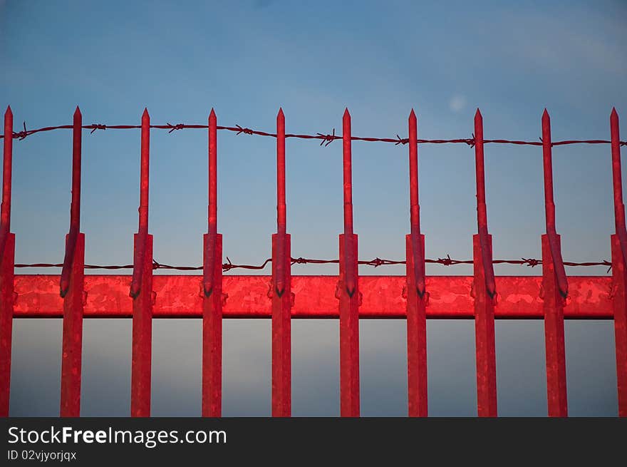 Red metal fence against blue sky