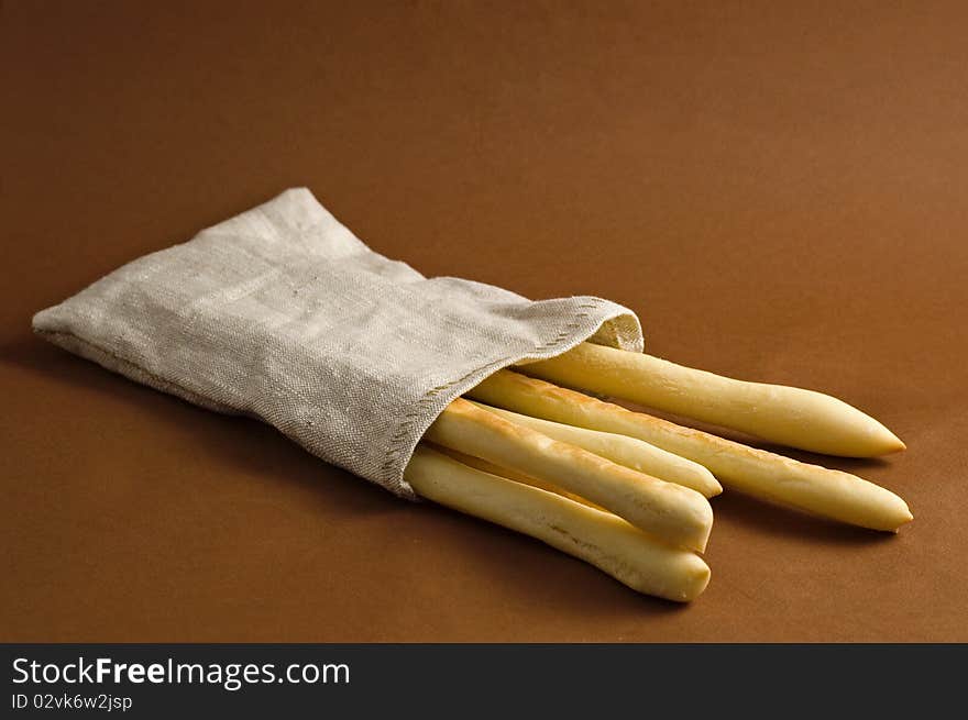 Bread sticks in sack on brown background