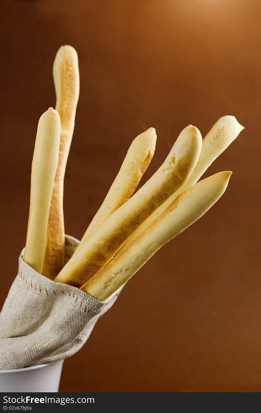 Bread sticks in sack on brown background