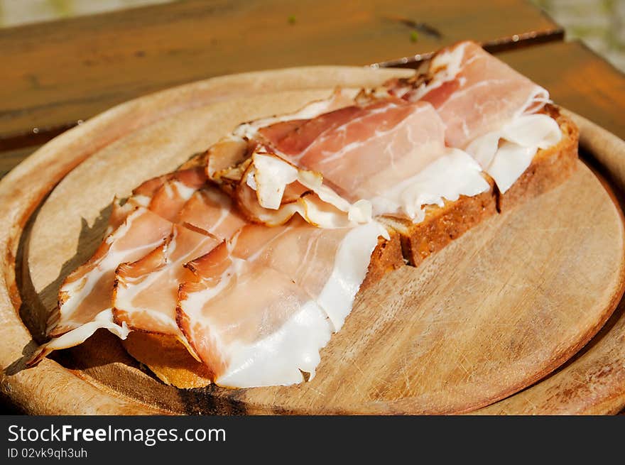 Bread with bacon on a wooden plate