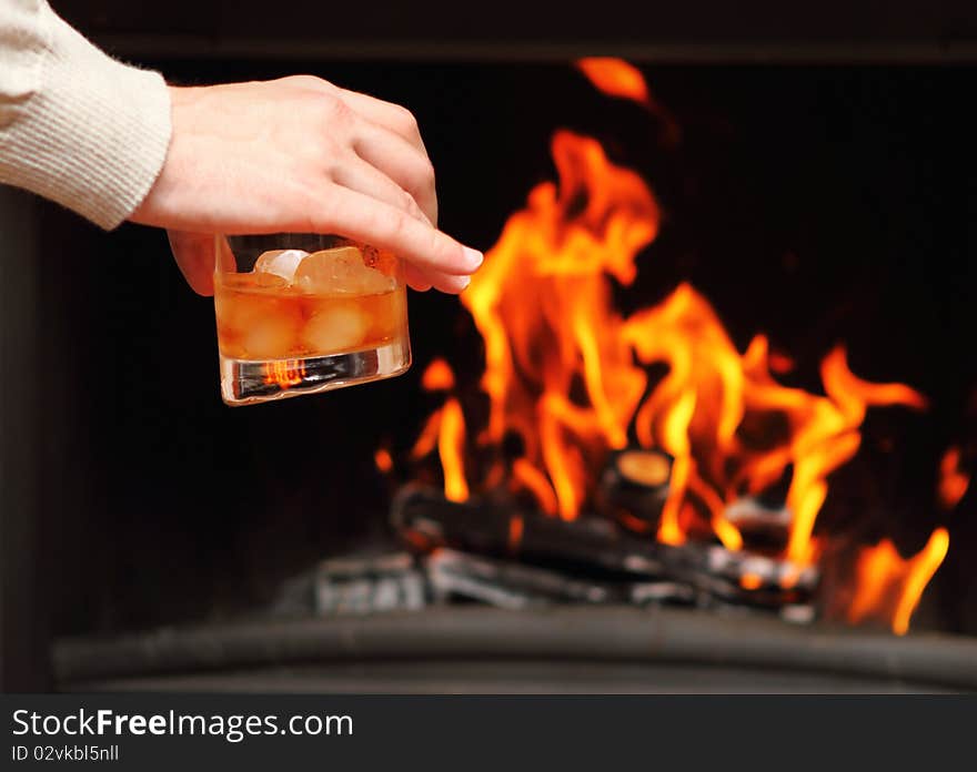 Man drinking whiskey by the fireplace