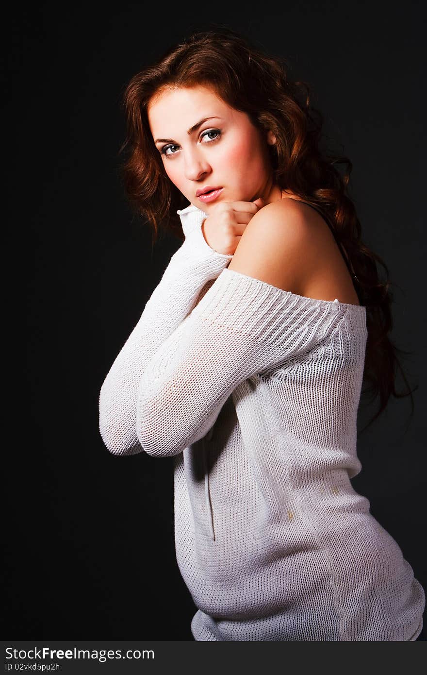 Portrait of a attractive young brunette in sweater on gray background