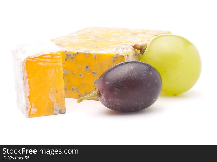Cheese and a slice of cheese with mould and two grapes. Isolated on white background. Cheese and a slice of cheese with mould and two grapes. Isolated on white background