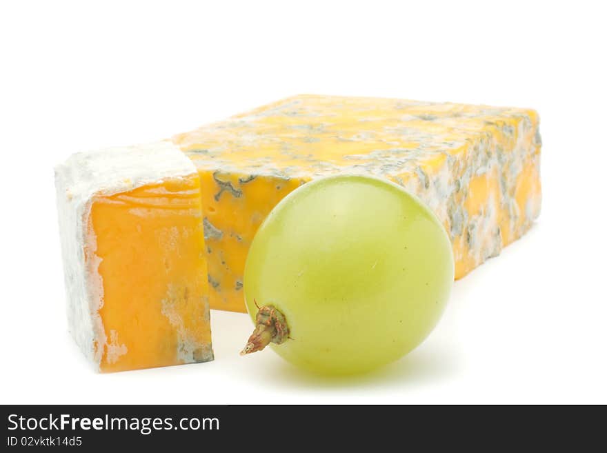 Cheese and a slice of cheese with mould and green grape. Isolated on white background. Cheese and a slice of cheese with mould and green grape. Isolated on white background