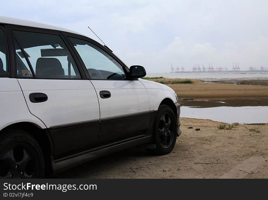 A car parked in front of a container terminal. A car parked in front of a container terminal