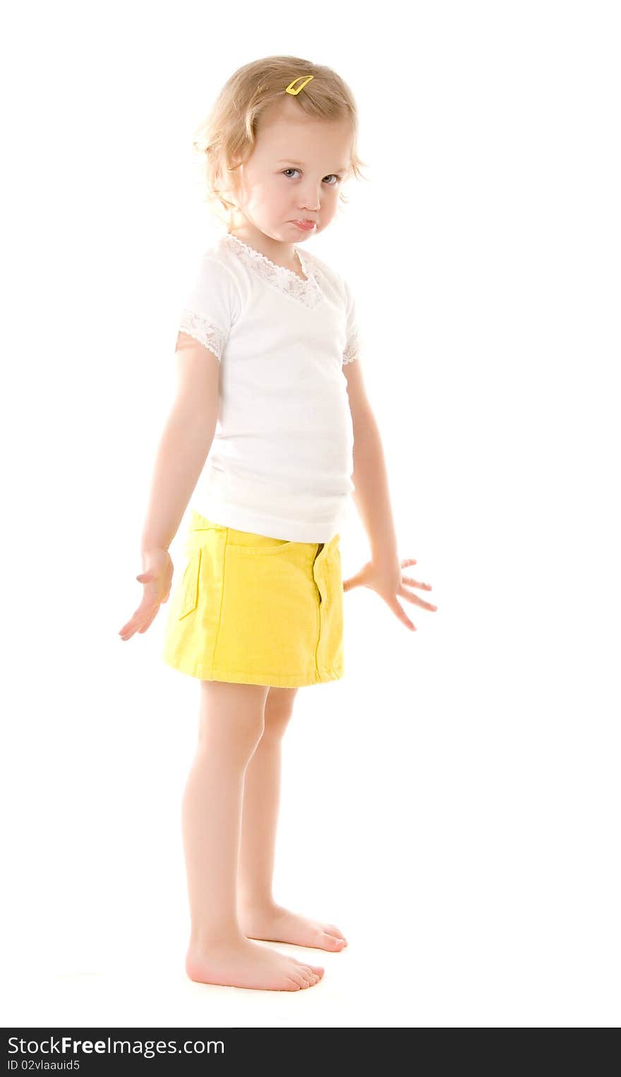 Fretful little girl wearing a yellow skirt standing on white background. Fretful little girl wearing a yellow skirt standing on white background