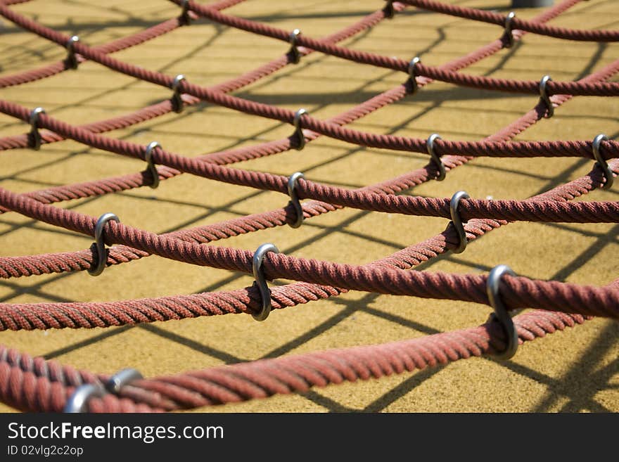 Big red ropes in perspective, in a playground, for children, together by a hook, one rope in detail at the front. Big red ropes in perspective, in a playground, for children, together by a hook, one rope in detail at the front