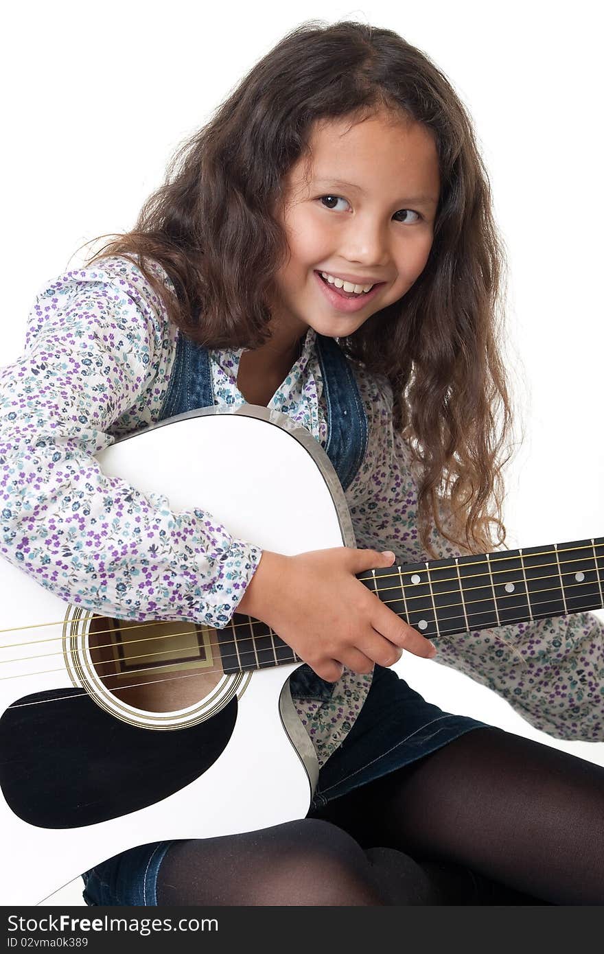 Girl plays the guitar, portrait of a child with music instrument before white background