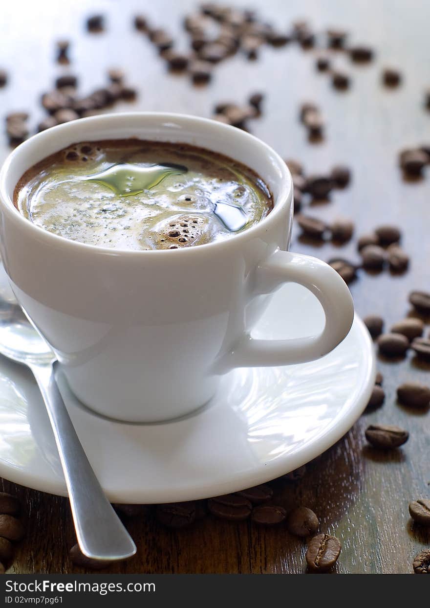 Cup of coffee with  coffee beans on background