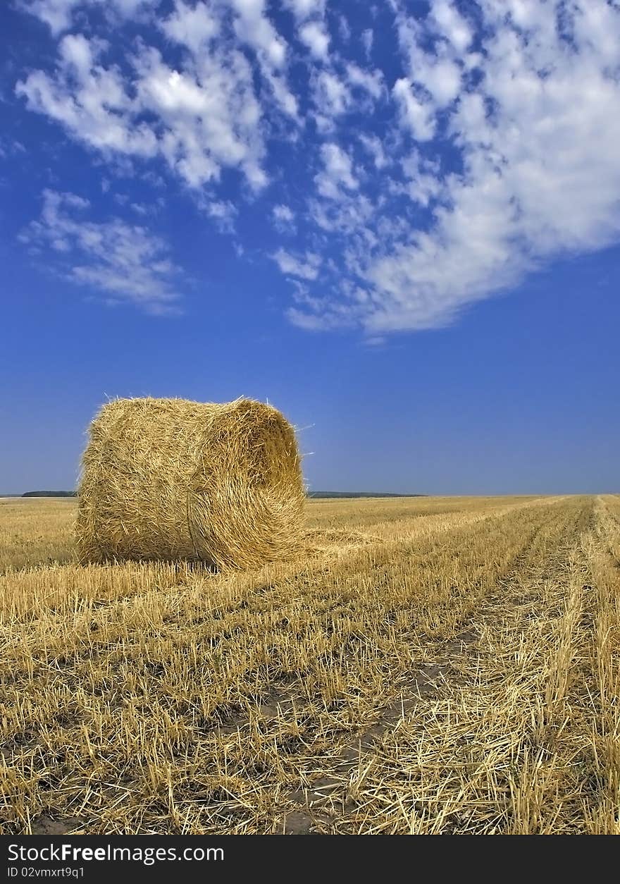 Straw stack in the field against the dark blue sky.