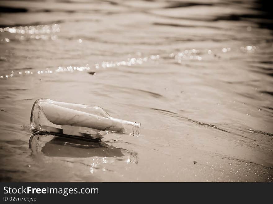 A Glass bottle with a letter washed up on a sandy beach. A Glass bottle with a letter washed up on a sandy beach