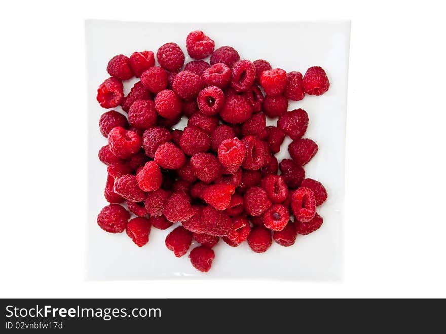 A heap of red raspberries on plate. Isolated on white