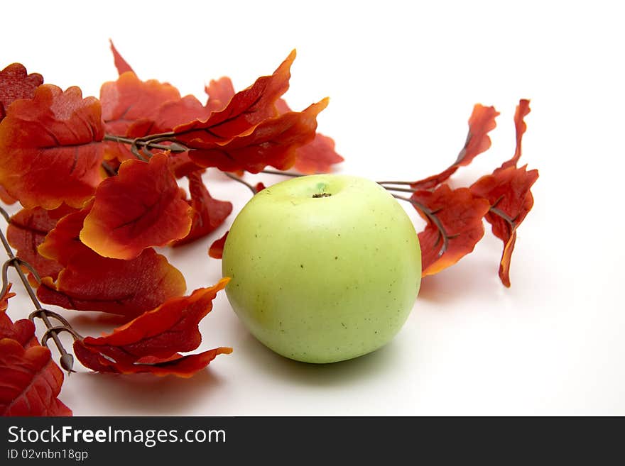 Artificial branch with red leaves and apple