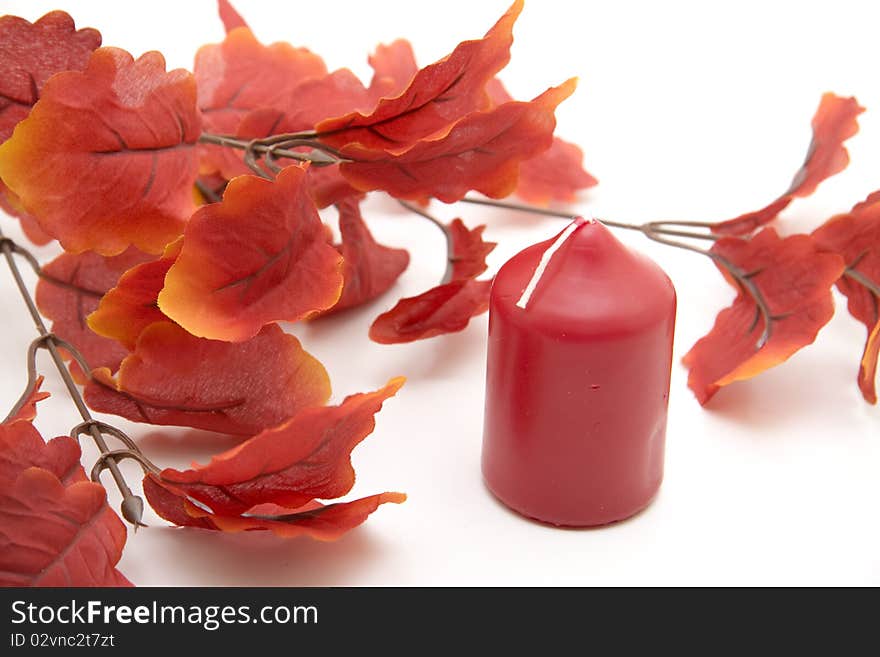 Artificial branch with red leaves and candle