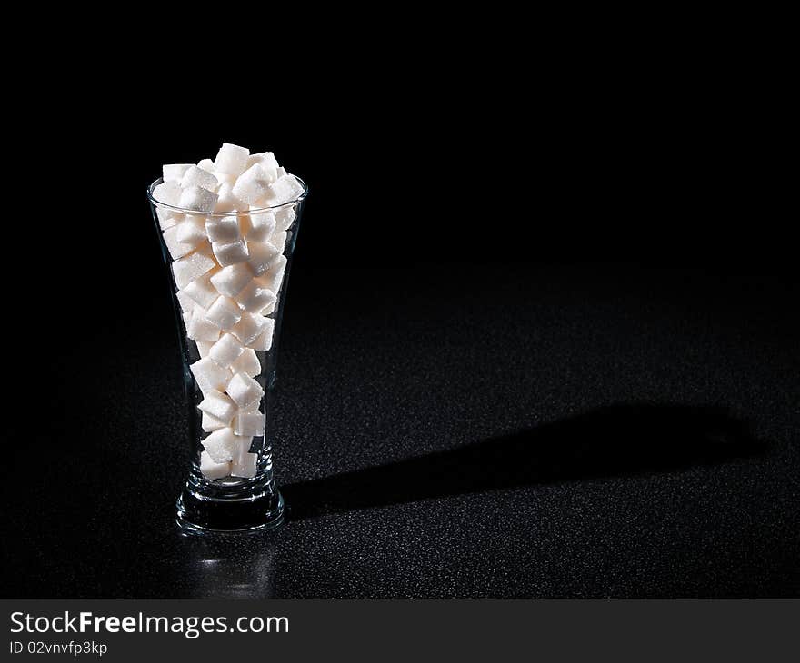 Glass of sugar tubes with long shadow in dark. Glass of sugar tubes with long shadow in dark