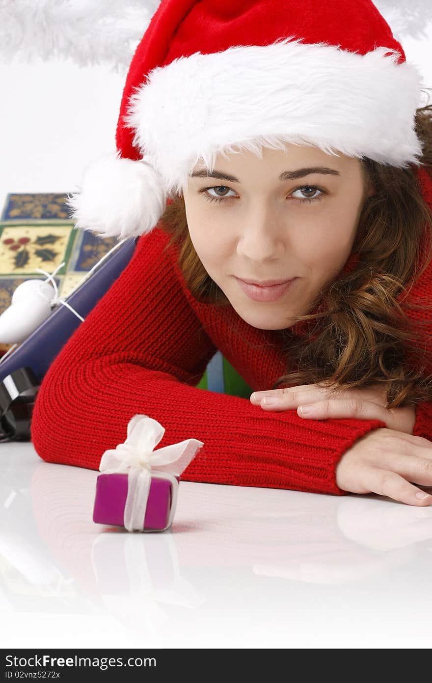 Beautiful young woman wearing santa hat next to christmas gift on white background