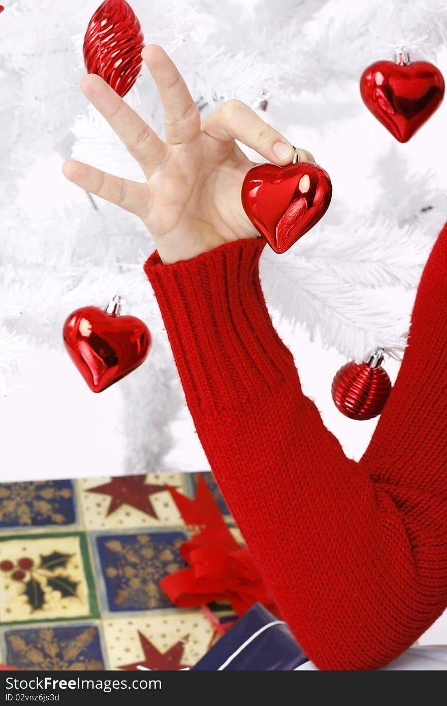 Hand holding a christmas heart near to a christmas tree